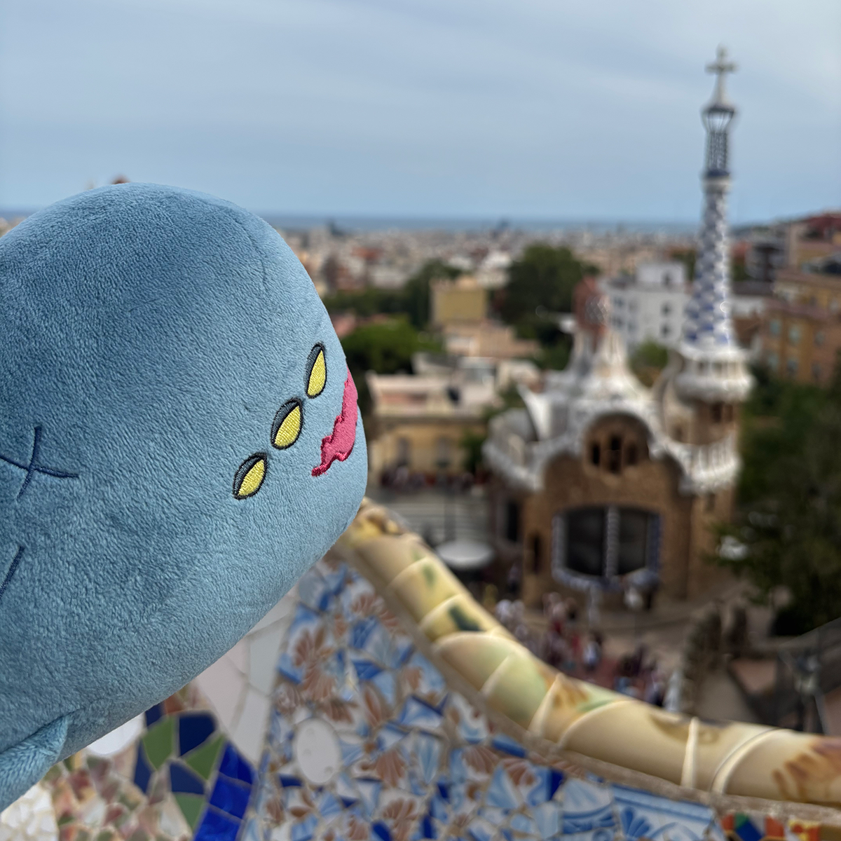 Picture of a Neow plush looking out at the view from Park Guell.